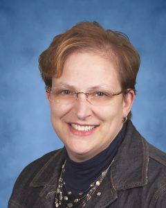 Photo of woman with short brown hair and glasses, smiling