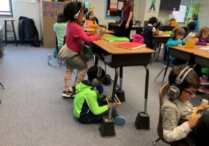 students with headphones working on a tablet