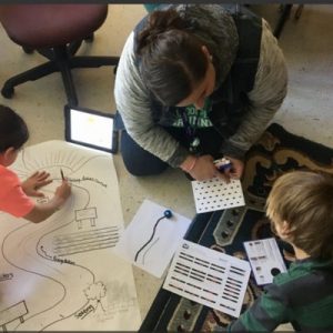 teacher working with students on ozobot project