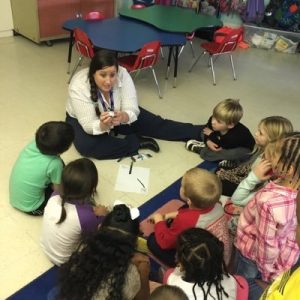 teacher with students sitting on the floor