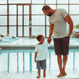 father and son hand-in-hand near a pool